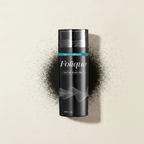Folique bottle with black hair fibre dust on cream background